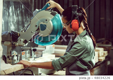 Busy and serious craftswoman grinding timbers with special machine. 48034226