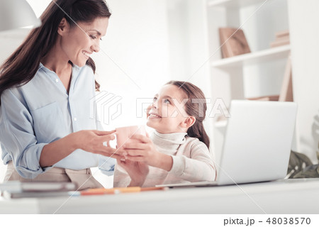Caring tender mother bringing daughter cup of tea to her child room Caring tender mother bringing daughter cup of tea to her child room 48038570