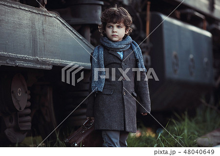 A little boy in a coat goes next to the train A little boy in a coat goes next to the train 48040649