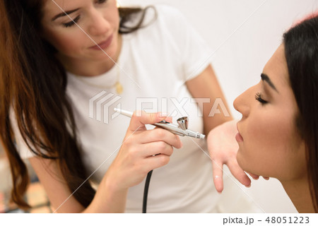 Make-up artist using aerograph making an airbrush make up 48051223