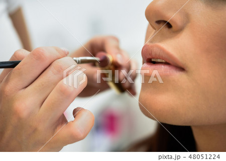 Makeup artist making up lips of an African young woman 48051224