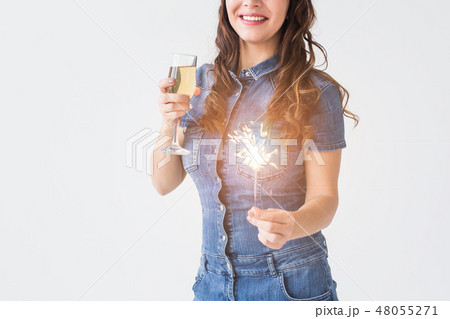 Celebration, drinks and holiday concept - close up of young woman with sparkler and glass of Celebration, drinks and holiday concept - close up of young woman with sparkler and glass of 48055271