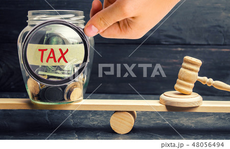Glass jar with coins and the inscription Tax Glass jar with coins and the inscription Tax 48056494