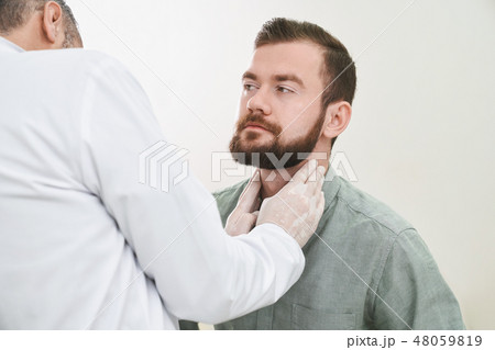 Bearded handsome man having neck and lymph nodes checked. 48059819