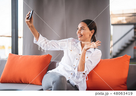 Cute young lady waiving her hand while having video call Cute young lady waiving her hand while having video call 48063419