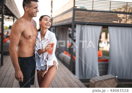 Positive couple standing outdoors and looking into the distance Positive couple standing outdoors and looking into the distance 48063528