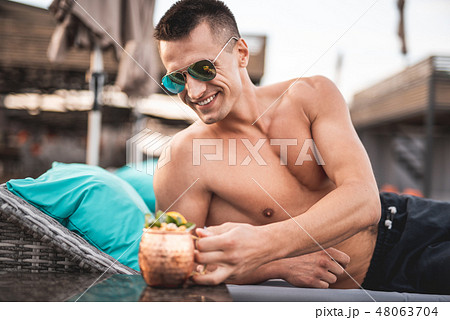 Shirtless handsome man putting his beverage on the table and smiling 48063704