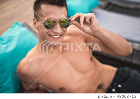 Handsome friendly man touching his sunglasses and smiling 48063715