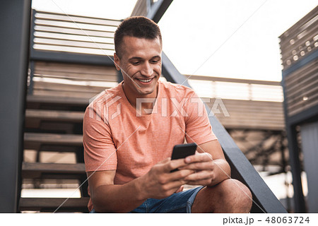Happy man sitting on the stairs and using his smartphone 48063724