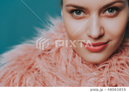Confident smiling young lady in peach fur coat 48063859