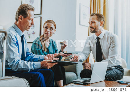 Curious lady drinking coffee while two businessmen talking Curious lady drinking coffee while two businessmen talking 48064071
