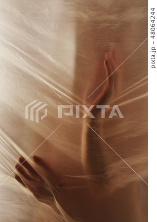 Hands through the clear film.Beautiful delicate feminine hands. A symbol of illusiveness and 48064244
