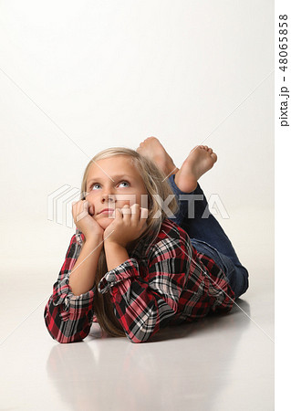 Girl with long blond hair is lying thoughtfully on the floor. White background 48065858