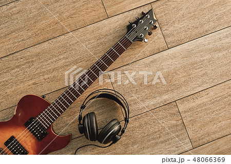 Guitar recording. An electric guitar and professional headphones on a wooden floor Guitar recording. An electric guitar and professional headphones on a wooden floor 48066369