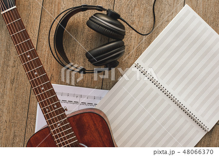 Close up view of guitar, professional headphones and musical notes laying on the wooden floor Close up view of guitar, professional headphones and musical notes laying on the wooden floor 48066370