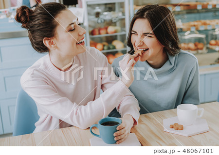 Overjoyed female friends eating tasty cookies together Overjoyed female friends eating tasty cookies together 48067101