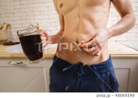 fit man with muscle body holding mug of dark beer 48069399