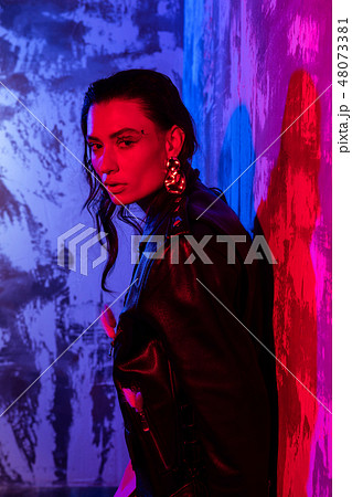 Nice dark haired woman standing near the colorful wall 48073381
