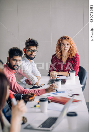 Mixed race people listening to presentation sitting in row at boardroom table 48075695