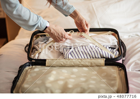 Woman in elegant clothes packing things into travel bag, departing from hotel 48077716