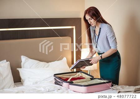 Woman in elegant clothes packing things into travel bag, departing from hotel 48077722