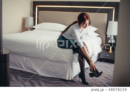 Business lady being tired after a long journey resting on bed in hotel room. Business lady being tired after a long journey resting on bed in hotel room. 48078239
