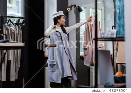 Young dark-haired asian pretty woman in trendy headwear looking serious Young dark-haired asian pretty woman in trendy headwear looking serious 48078504