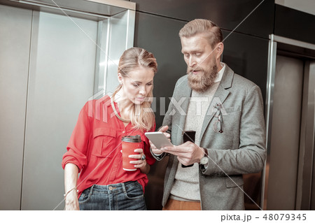 Attentive longhaired girl staring at screen of gadget Attentive longhaired girl staring at screen of gadget 48079345