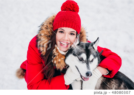 Woman caresses the Husky dog in winter forest Woman caresses the Husky dog in winter forest 48080307