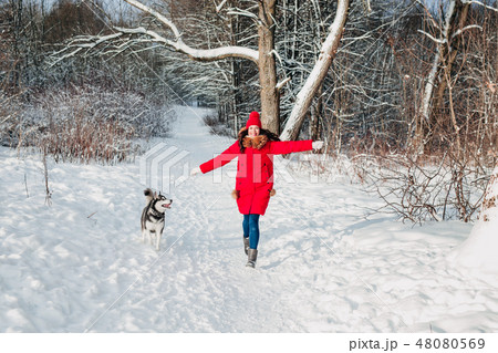 Young woman playing with her Husky dog in winter park Young woman playing with her Husky dog in winter park 48080569