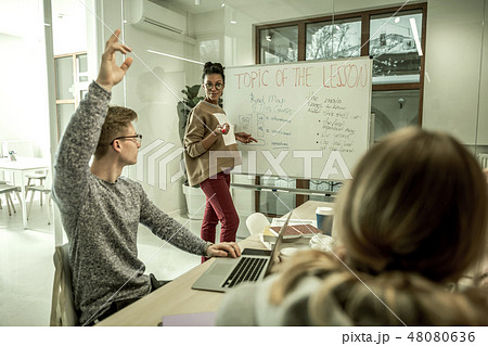 Blonde student wearing glasses raising hand having question 48080636