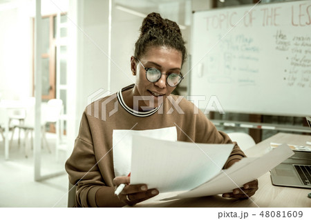 African-American teacher feeling involved in checking tests of her students 48081609