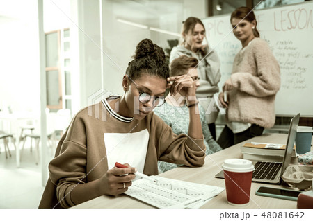Office trainee wearing glasses feeling busy studying new material Office trainee wearing glasses feeling busy studying new material 48081642