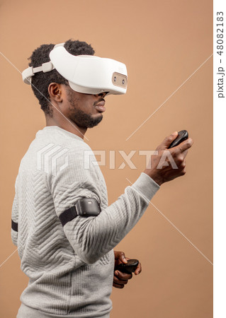Black man wearing 3d vr glasses, playing videogame, holding joystick in hands Black man wearing 3d vr glasses, playing videogame, holding joystick in hands 48082183