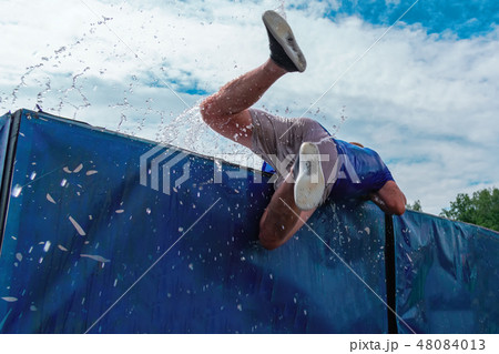 Low angle view of man getting out water obstacle. 48084013