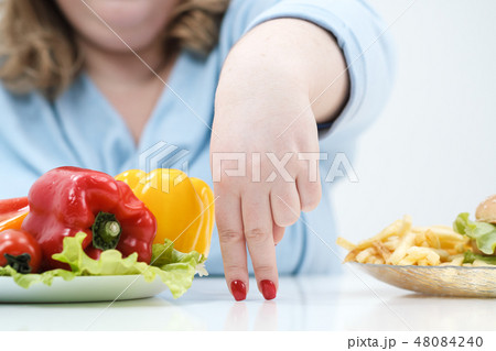 Fingers of a young lush fat woman in casual blue clothes on a white background, the choice between Fingers of a young lush fat woman in casual blue clothes on a white background, the choice between 48084240