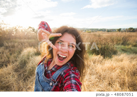 Travel, vacation and holiday concept - Funny young woman taking selfie over beautiful landscape Travel, vacation and holiday concept - Funny young woman taking selfie over beautiful landscape 48087051