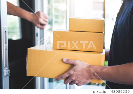 Home owner open door to delivery man standing with parcels in ha Home owner open door to delivery man standing with parcels in ha 48089239
