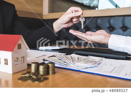 Estate agent giving house keys to client after signing agreement Estate agent giving house keys to client after signing agreement 48089327