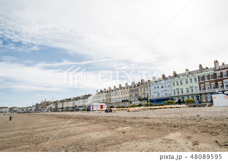 イギリス郊外の海岸沿いの街並み　砂浜脇に立つ様々な色の大きい長屋 48089595