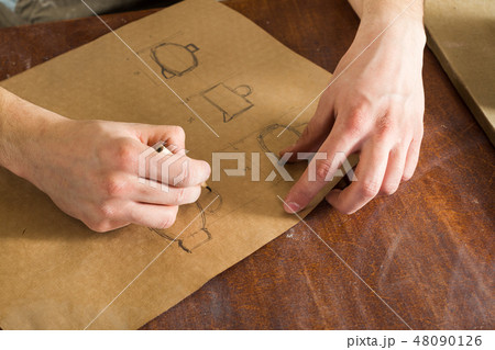 the hand of a man sketching dishes on crafting paper with a pencil, handcrafted work. horizontal 48090126