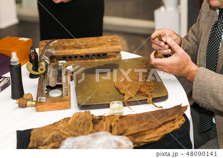 Process of making traditional cigars from tobacco leaves using a mechanical device and press. Leaves Process of making traditional cigars from tobacco leaves using a mechanical device and press. Leaves 48090141