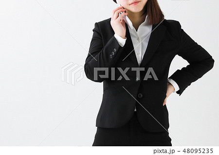 白背景スーツの女性が携帯電話ガラケーで電話している姿の写真素材
