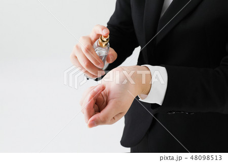 白背景でスーツの女性が手元に香水をつける姿手元アップ 48098513