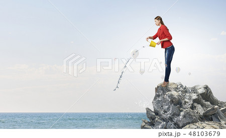 Girl pouring water from bucket 48103679