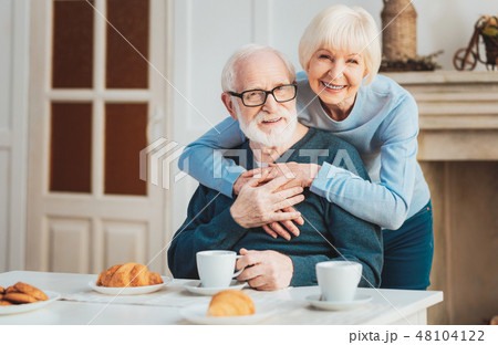 Cute couple of pensioners having warm croissants during breakfast Cute couple of pensioners having warm croissants during breakfast 48104122