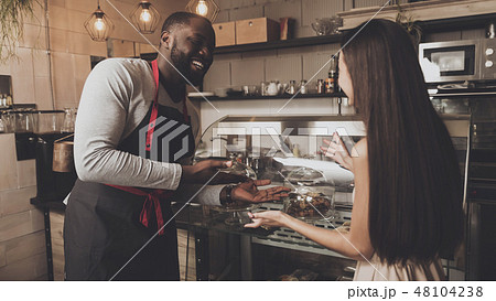 Male barista helps a girl to choose a dessert 48104238