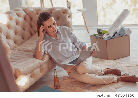 Busy young woman being attentive while working with a laptop Busy young woman being attentive while working with a laptop 48104250