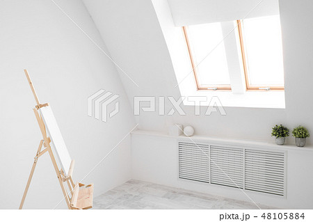White and bright studio with a window. Workspace of the artist. Easel, canvases and plaster figures 48105884
