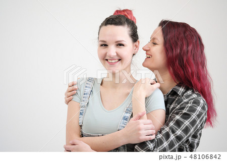 Two girls hug on a white background. Homosexual lesbian couple. Casual clothes. Two girls hug on a white background. Homosexual lesbian couple. Casual clothes. 48106842